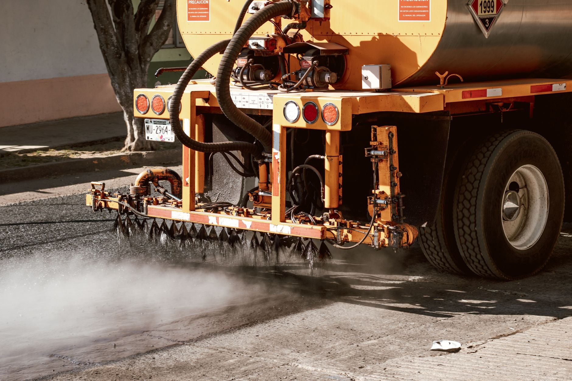 Close-up of a truck performing road maintenance with spray equipment.